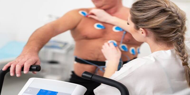 Una médica le coloca electrodos en el pecho a un paciente para realizarle un test de esfuerzo.