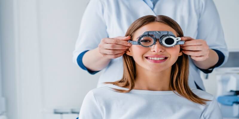 Mujer realizando una prueba de refracción ocular en un consultorio oftalmológico.