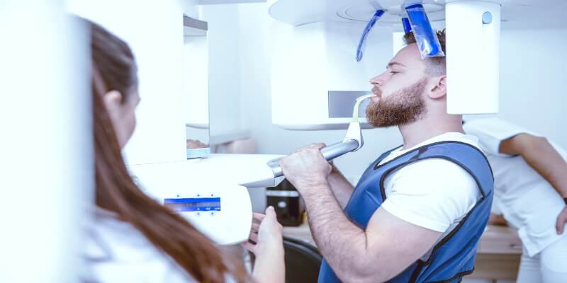 Un hombre realizándose una radiografía panorámica en un consultorio médico.