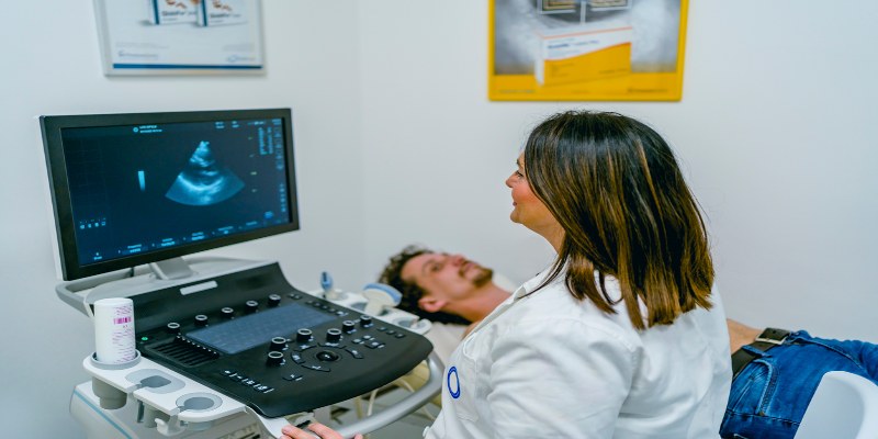 Un hombre realizándose un ecocardiograma Doppler en un consultorio médico