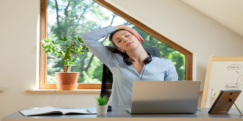 Mujer estirándose en su escritorio durante una pausa activa.