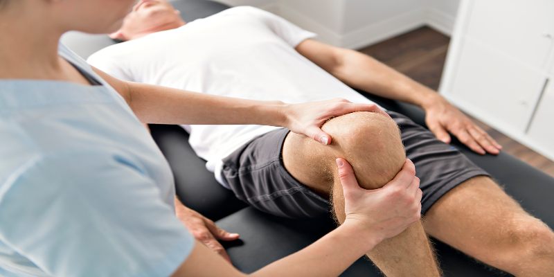 Doctora examinando la rodilla de un paciente.