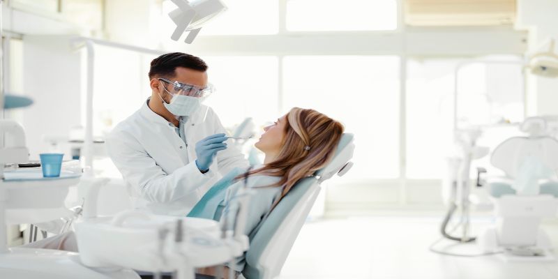 Periodoncista realizando un tratamiento dental a un paciente en una consulta.