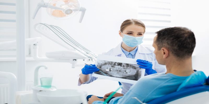 Odontóloga mostrando una radiografía dental a un paciente durante una consulta.