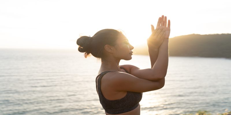 Mujer practicando yoga al aire libre.