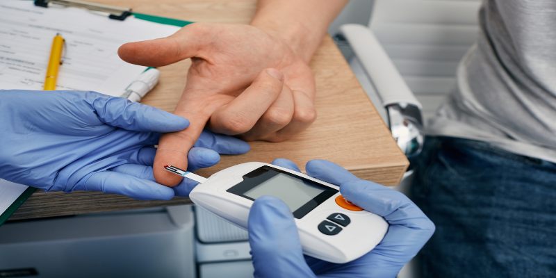 Médico verificando el nivel de glucosa en sangre del paciente diabético con un glucómetro.